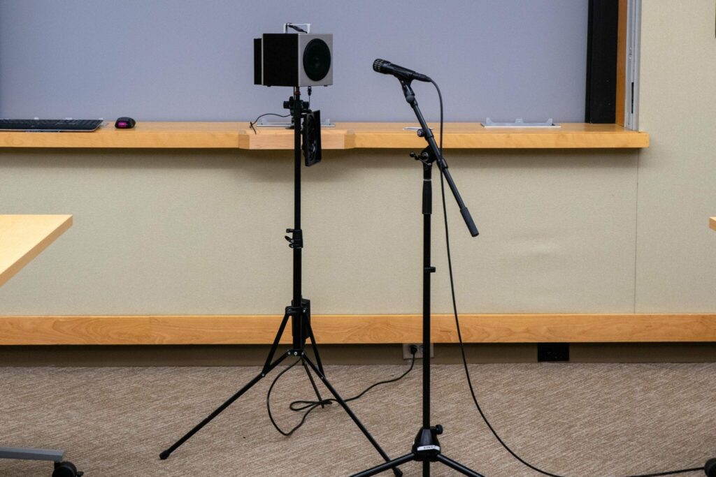 Image of a speaker and a microphone pointed at the speaker measuring the AV equipment efficiency of properly amplifying sound across the room.