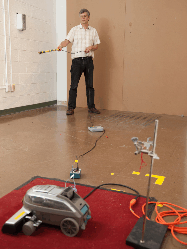 Photograph of Acentech Principal David Bowen measuring sounds from different components of a vacuum cleaner.